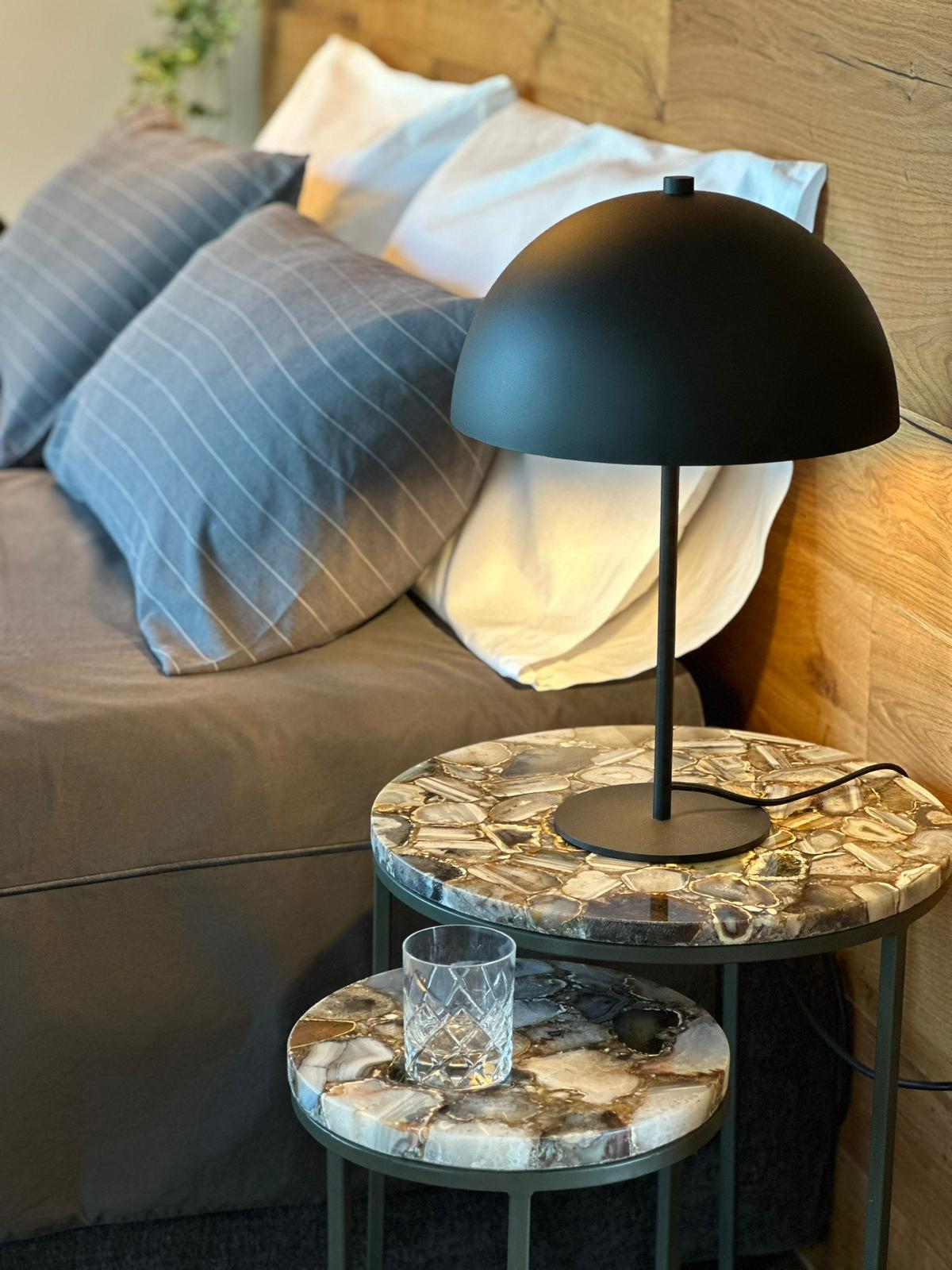 Black dome bedside lamp on agate stone side tables — design detail at Villa Irene Langhe